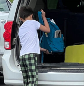 Kid putting backpack into car