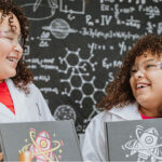 Two smiling children holding STEM boxes